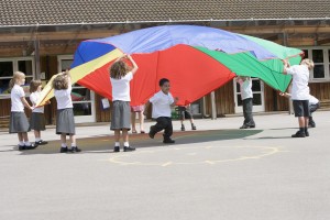 Young children playing with a parachute in a playground